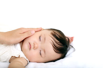 Fototapeta na wymiar 白背景で寝ている女の子の赤ちゃんの頬を撫でる母の手。愛情,家族,母性のイメージ