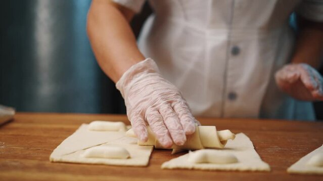 Woman making a croissant from dough in the kitchen