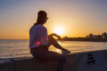 woman sitting and watching sunrise on a bench.