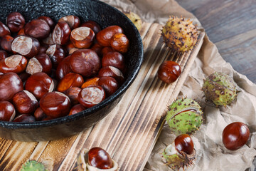 Close up view of chestnuts in a cast iron pan on a wooden background