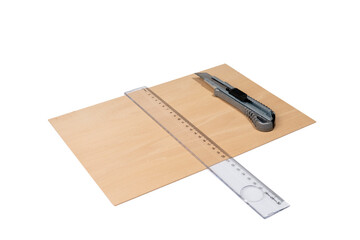 Wooden plate on a white background, plastic ruler, utility knife, cuttable