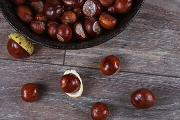 Close up view of chestnuts in a cast iron pan on a wooden background