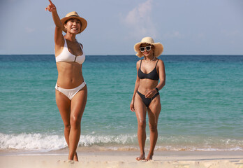  Two women walking on beach, Pretty young women in bikini walking on tropical beach , summer...