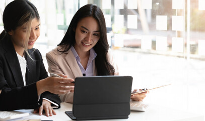 Two beautiful young asian businesswoman working together using digital tablet at office.