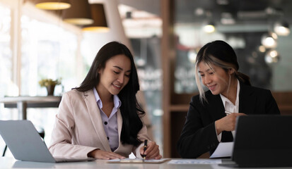 Two beautiful young asian businesswoman working together using digital tablet at office.