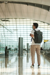 Young male wearing face mask with bagckpack walking in airport, protection Coronavirus disease infection, Asian man traveler. Time to travel after vaccine booster dose concept