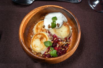 Syrniki, cottage cheese fritters with cherry jam and sour cream. Rustic style.