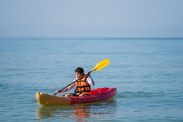 Fototapeta na wymiar man in life jacket paddling a kayak boat in sea