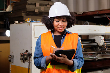 African American female engineer worker in safety uniform and hard hat, quality inspect by tablet,...