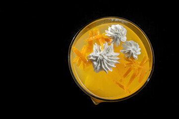 Delicious orange jelly with pieces of zest in a glass on a black background.