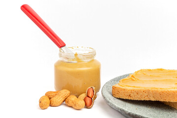 Bread with peanut butter and glass with peanut butter and knife on a white background