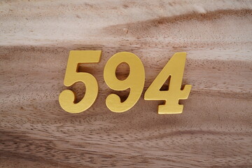 Golden Arabic numerals on a real brown and white wooden floor number 594