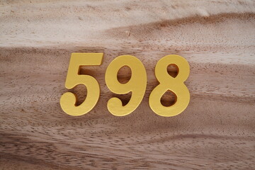 Golden Arabic numerals on a real brown and white wooden floor number 598