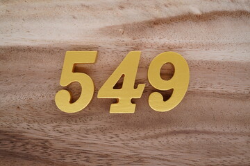 Golden Arabic numerals on a real brown and white wooden floor number 549