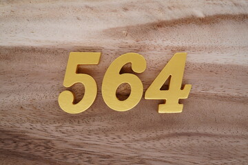 Golden Arabic numerals on a real brown and white wooden floor number 564