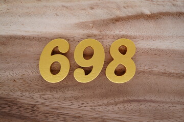 Golden Arabic numerals on a real brown and white wooden floor number 698