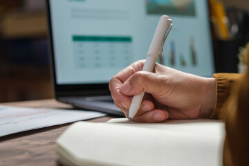 close uop woman hand writing on notebook at worknig desk at home