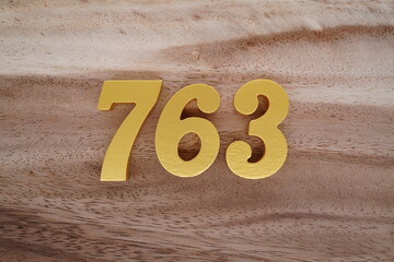 Golden Arabic numerals on a real brown and white wooden floor number 763