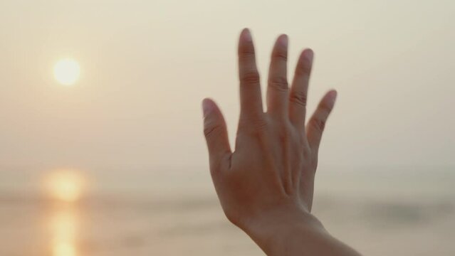 Woman waving hand say goodbye or parting with sunset alone on the seaside, Time to go farewell