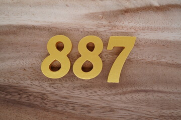 Golden Arabic numerals on a real brown and white wooden floor number 887