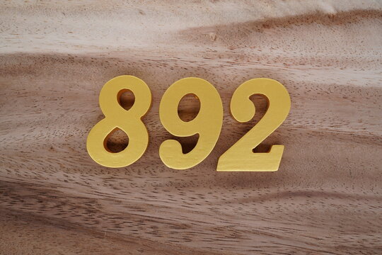 Golden Arabic numerals on a real brown and white wooden floor number 892