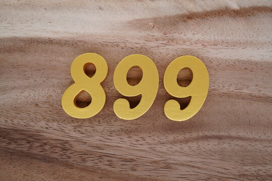 Golden Arabic numerals on a real brown and white wooden floor number 899