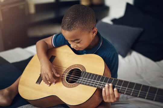 Music stimulates all the important functions of our brain. Shot of a young boy playing the guitar at home.