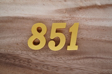 Golden Arabic numerals on a real brown and white wooden floor number 851