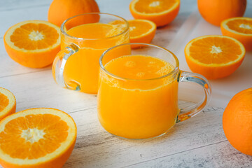 Oranges and fresh squeezed orange juice close up on wooden background