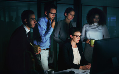 Overtime is just a part of the job. Cropped shot of a diverse group of businesspeople gathered around a single computer in their office.