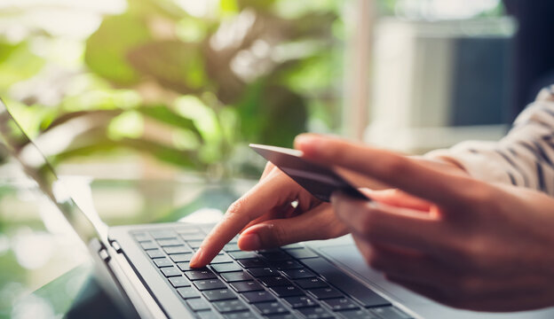 Hand holding credit cards and using laptop for shopping online with payment on internet banking.