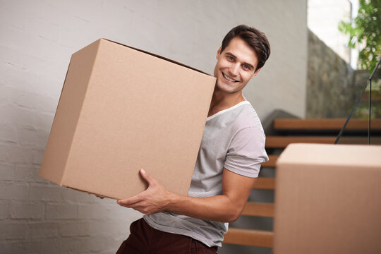 Cant wait to get to my new place. A happy young man moving packed cardboard boxes in his home.