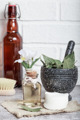 Laurel natural massage oil in a glass bottle. Cosmetic homemade tonic. Bay leaf in a mortar with a pestle