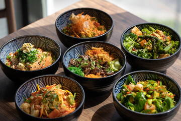 Poke bowls and other gourmet foods, with drinks and sushi on the table,
