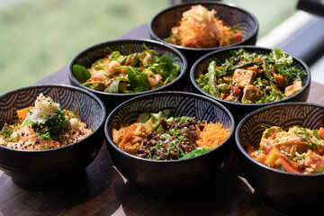 Poke bowls and other gourmet foods, with drinks and sushi on the table,