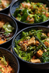 Poke bowls and other gourmet foods, with drinks and sushi on the table,