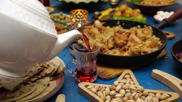 Moroccan mint tea. Ramadan iftar Eid. Muslim family has dinner at home. Falafel, samosa, chickpeas, beans, pita bread, pilaf, tajine, couscous, dates, olives. Eid Al Fitr holiday celebration