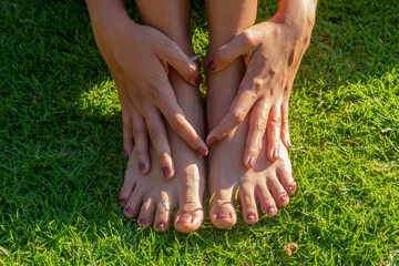 A female  is petting her barefoot on a lawn