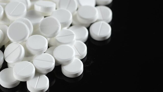 Many white round pills. Pharmaceutical production. Drugs on the production line. Moving background. close-up. view from above. white medical pills rotating closeup. Pills and drugs. Pharmaceutical