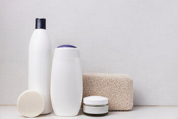Preparation for hotel spa treatment or home bath procedure. Gray bathroom shelf with accessories and cosmetics. Shampoo, shower gel, hair conditioner, washcloth, soap, cream glass bottle, white soap