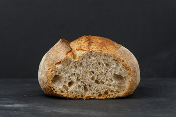 Cross-section of rustic sourdough bread on a black table