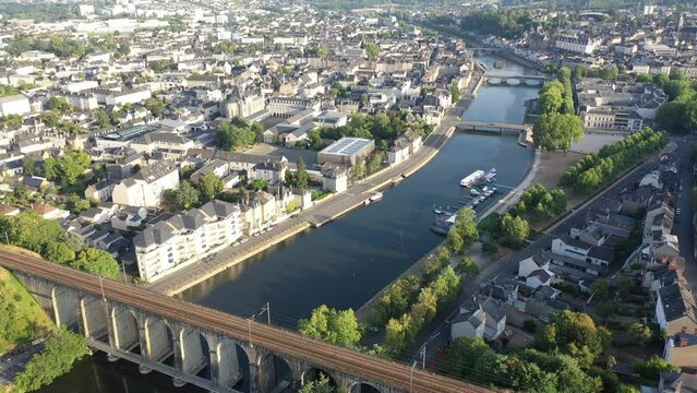 General aerial view of Laval town overlooking arched railway bridge across Mayenne River on summer day, France. High quality 4k footage