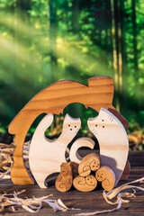 Wooden puzzle in the form of a handmade cat family on the background of the forest