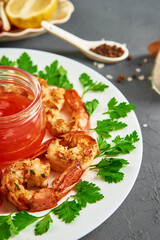 Grilled shrimps on white plate with fresh parsley, spices and lemon, fried prawns with sauce in jar