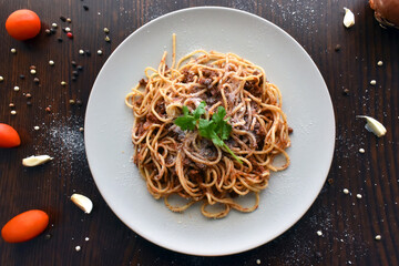Spaghetti Bolognese with minced beef, onion, chopped tomato, garlic, olive oil, stock cube, tomato puree and Italian herb. Traditional Italian food on a plate.  Flat lay top view photo.  