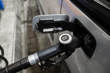 A pistol with diesel fuel in the mouth of a gas tank at a gas station. Selective focus. The concept...