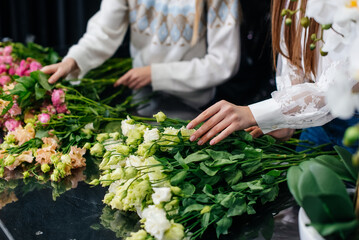 Close-up of women's hands collecting and making beautiful festive bouquets in a cozy flower shop. Floristry and bouquet making in a flower shop. Small business.