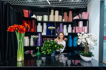 A young woman florist accepts an order by phone for the production of a beautiful festive bouquet....