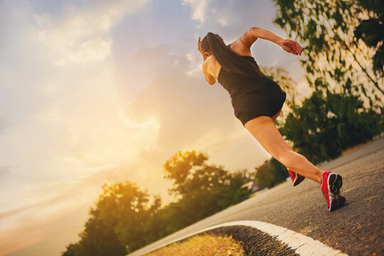 Silhouette of young woman start running at road track. Fit runner fitness runner during outdoor workout with sunset background.	Selected focus