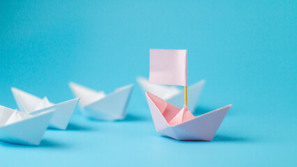 Leadership concept. Pink paper ship with flag lead among paper ship white. One leadership leads...